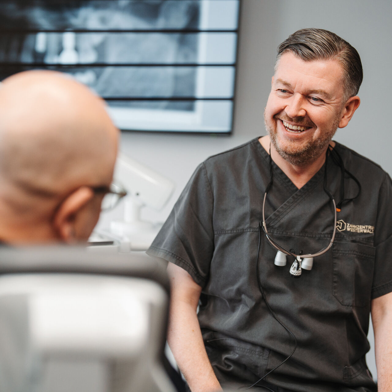 Zahnarzt lächelt Patienten vertrauensvoll an