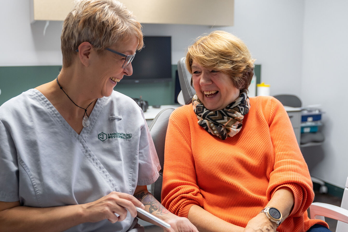 Dentalhygienikerin lacht mit Patientin im Behandlungszimmer
