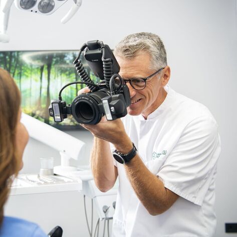 Zahntechniker fotografiert Zähne einer Patientin