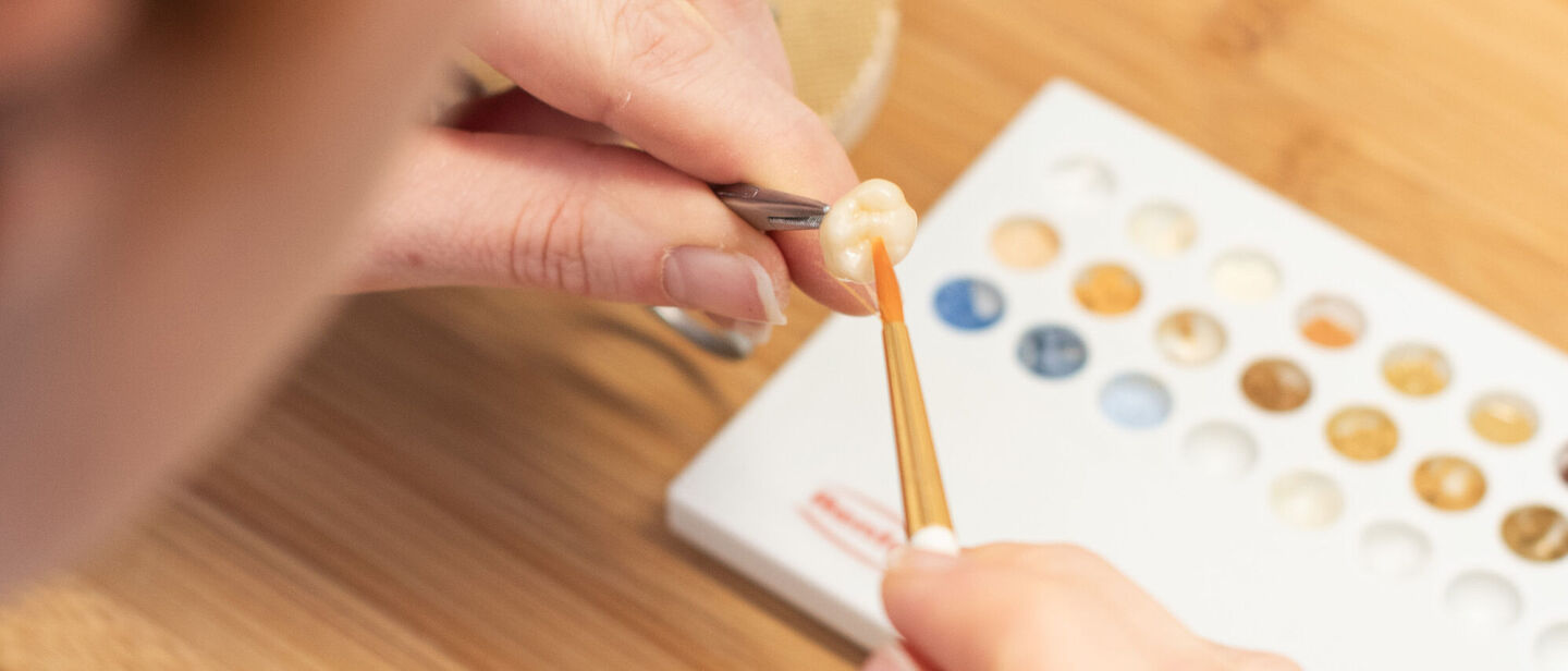 Zahntechnikerin bemalt Zahnersatz