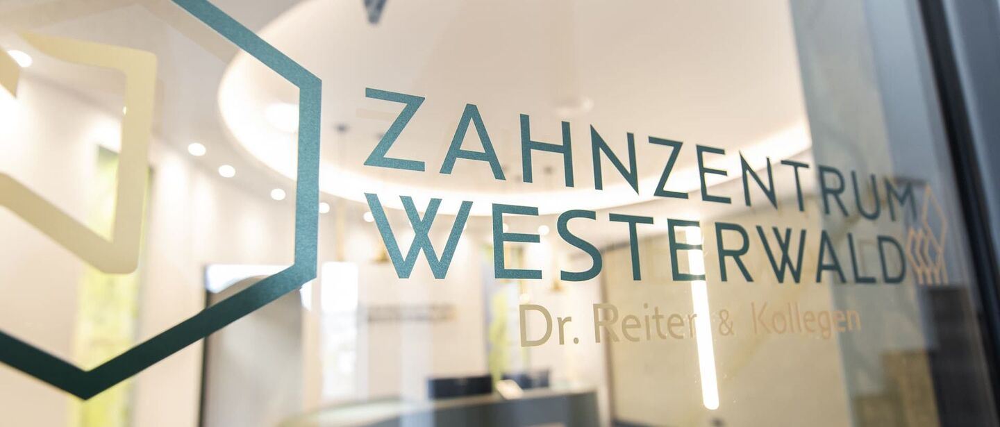 Glastür mit Logo und Blick in den Empfangsbereich