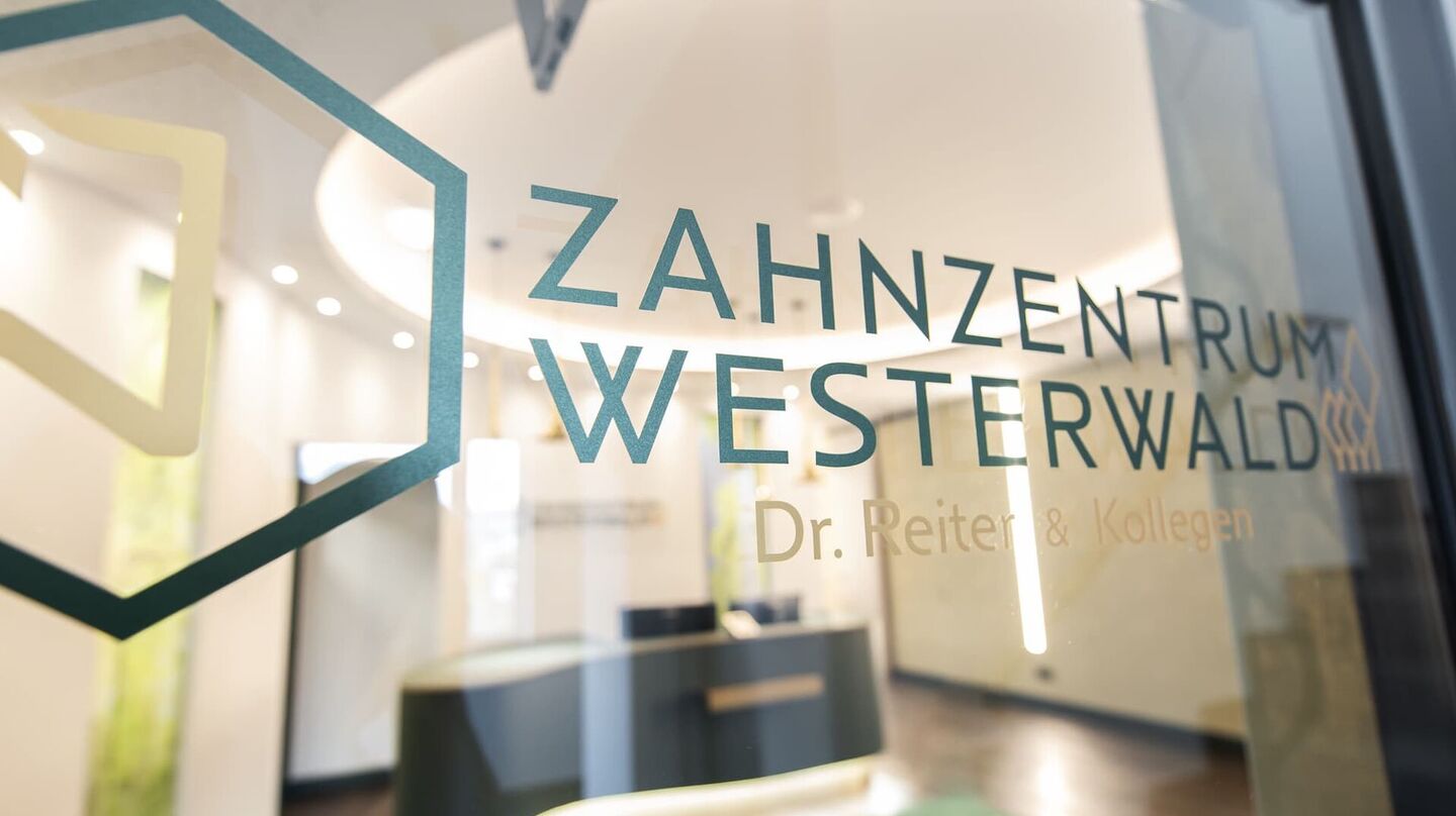 Glastür mit Logo und Blick in den Empfangsbereich