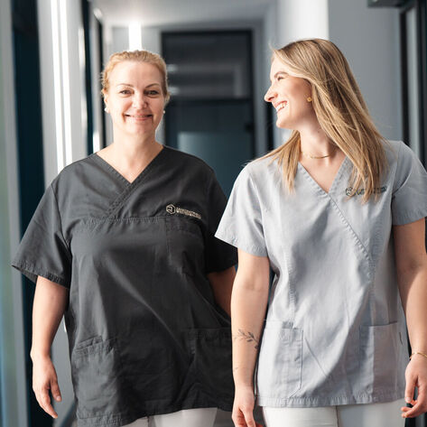 Zahnärztin und ZFA laufen über den Gang